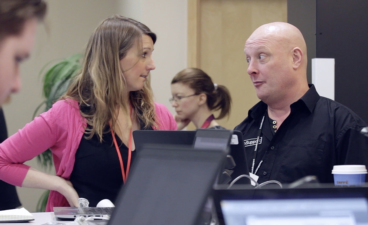 People talking with computer in foreground