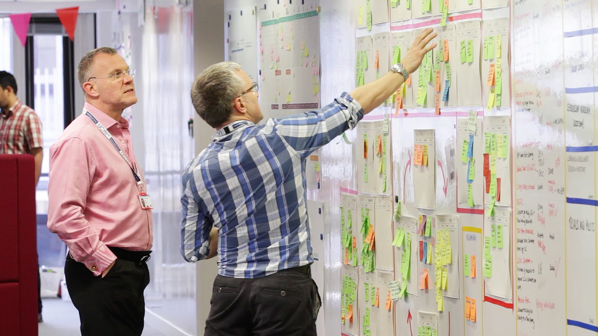 Image of two men looking at post-its on a whiteboard