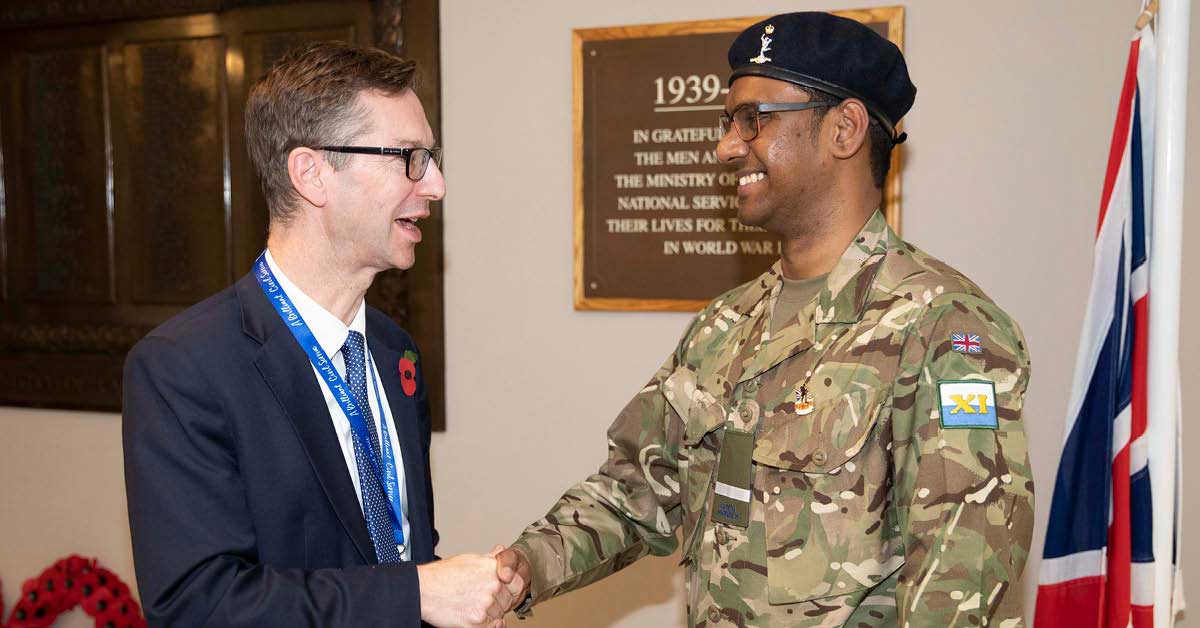 Nava in his Royal Corps uniform shaking hands with Peter Schofield DWP Permanent Secretary 