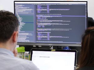 Man working on a computer. There are lines of code on the screen in front of him.