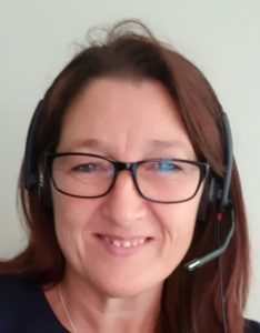 Tina smiling at the camera, wearing glasses and a headset