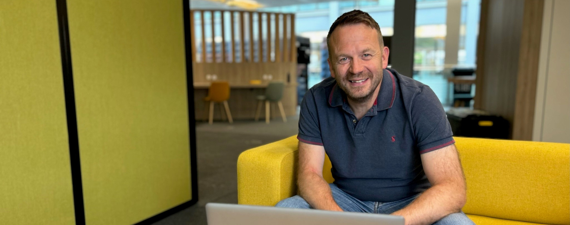 A man, sat in a DWP collaboration zone, smiling.