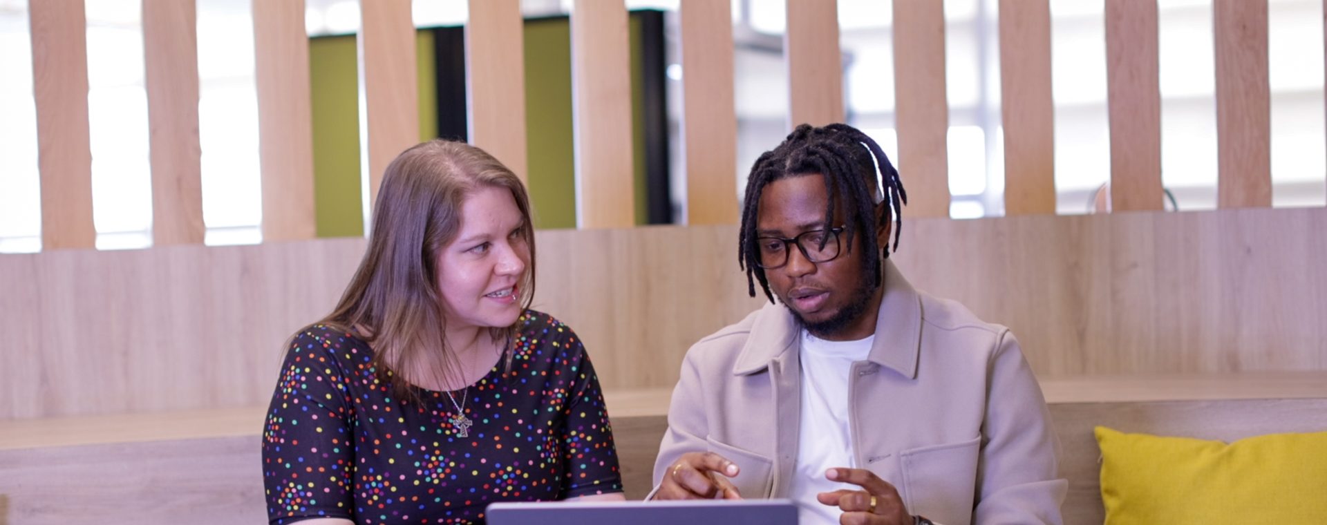 A female and male colleague talking to eachother whilst looking at a laptop.